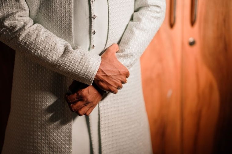 Close-up of hands on an embroidered gold sherwani